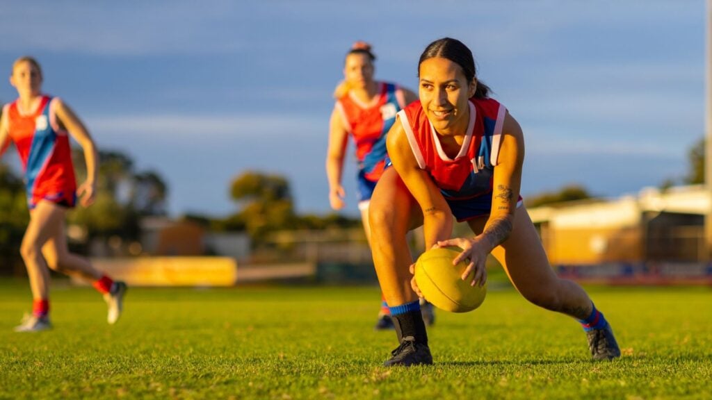 Adolescent girls playing AFL on a field