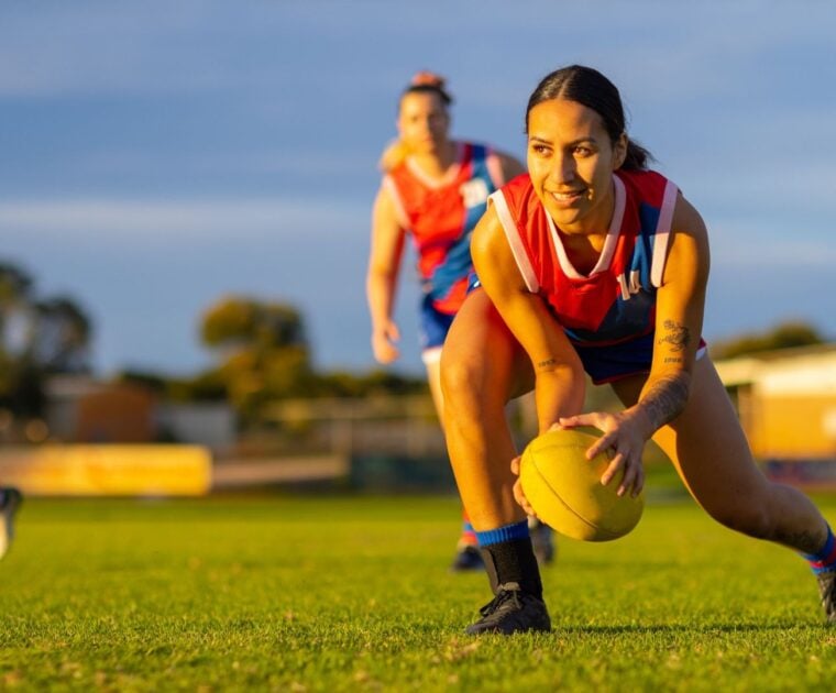 Adolescent girls playing AFL on a field