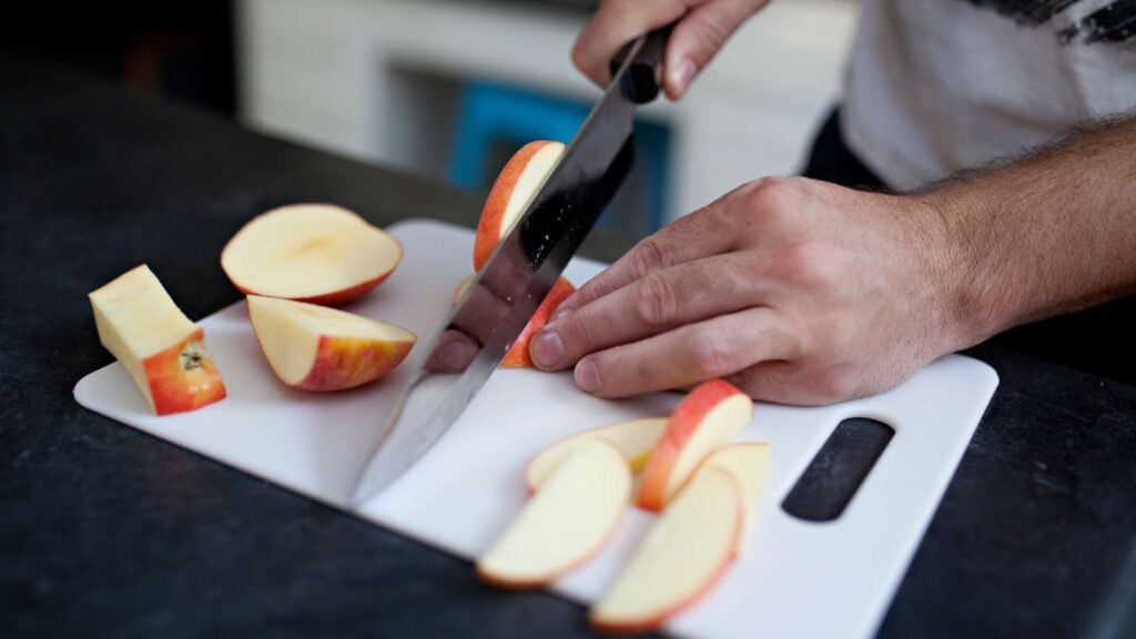 Person cutting apple slices on a chopping board