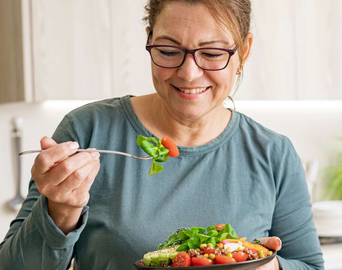 Woman eating healthy vegetable and legume salad in the kitchen