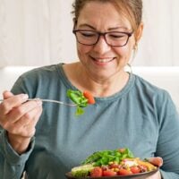 Woman eating healthy vegetable and legume salad in the kitchen