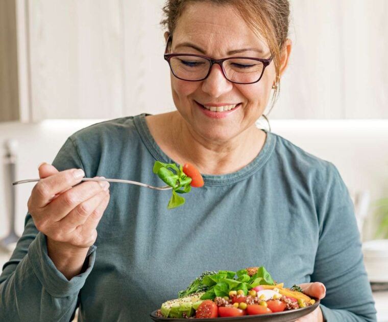 Woman eating healthy vegetable and legume salad in the kitchen