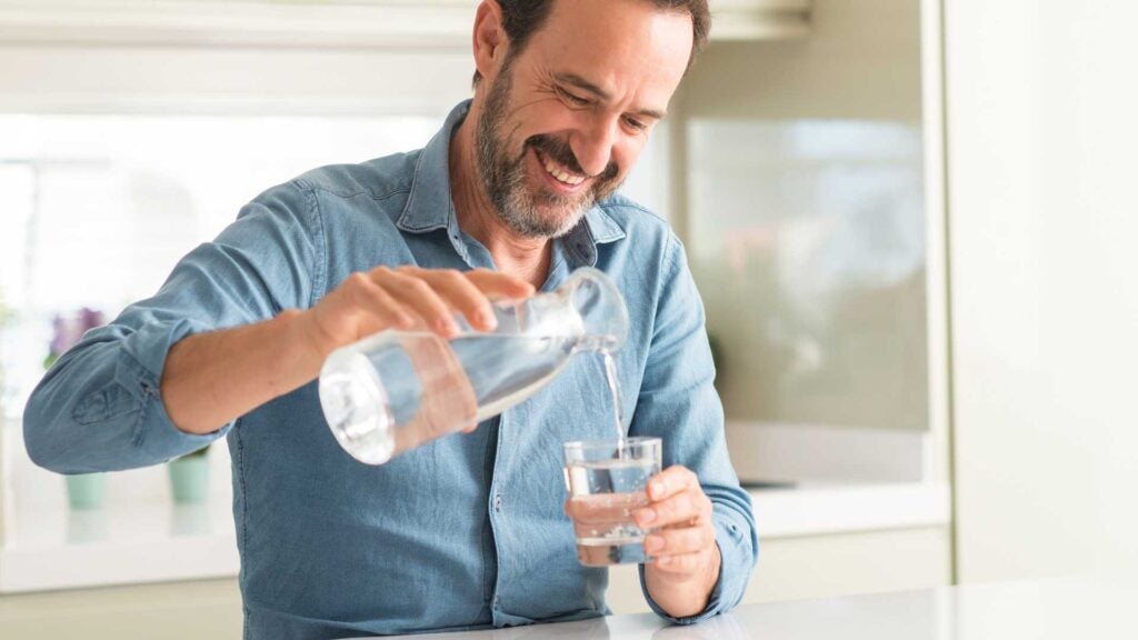 Man pouring a glass of water in the kitchen