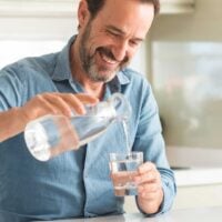 Man pouring a glass of water in the kitchen