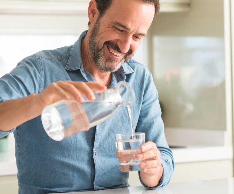 Man pouring a glass of water in the kitchen