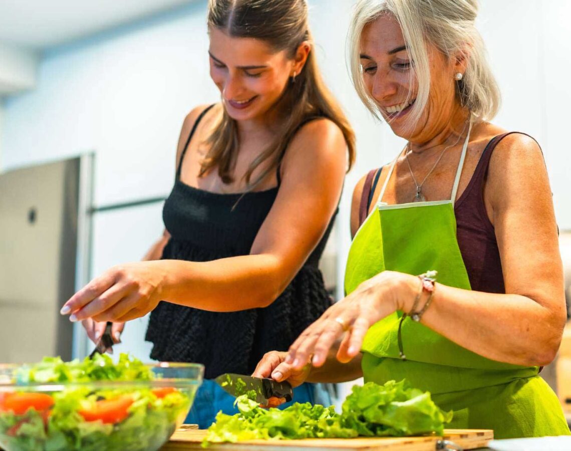 Mother and daughter enjoying making healthy leafy salad in the kitchen