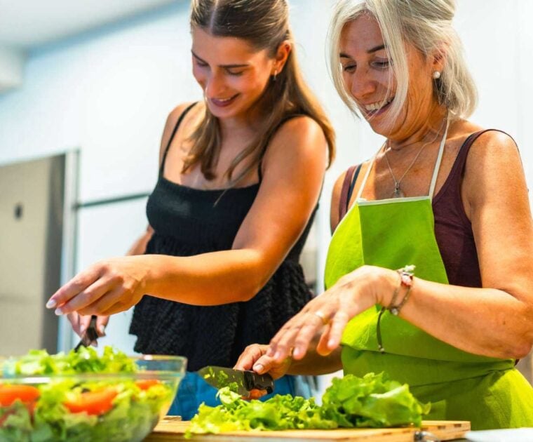 Mother and daughter enjoying making healthy leafy salad in the kitchen