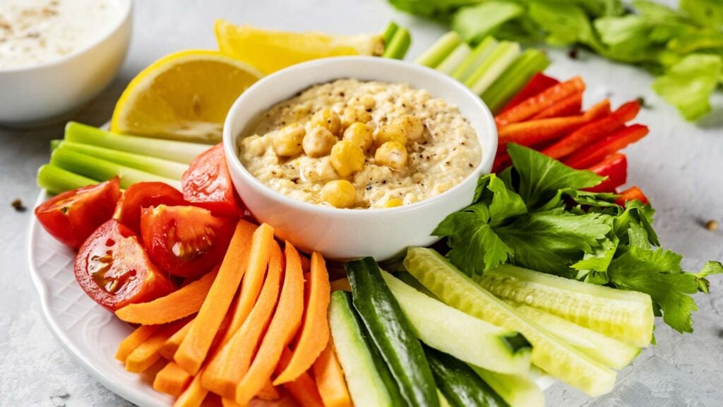 Share plate of colourful vegetable sticks with hummus dip