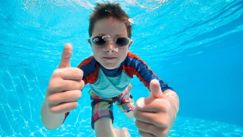 ves thumbs up underwater in the pool wearing goggles