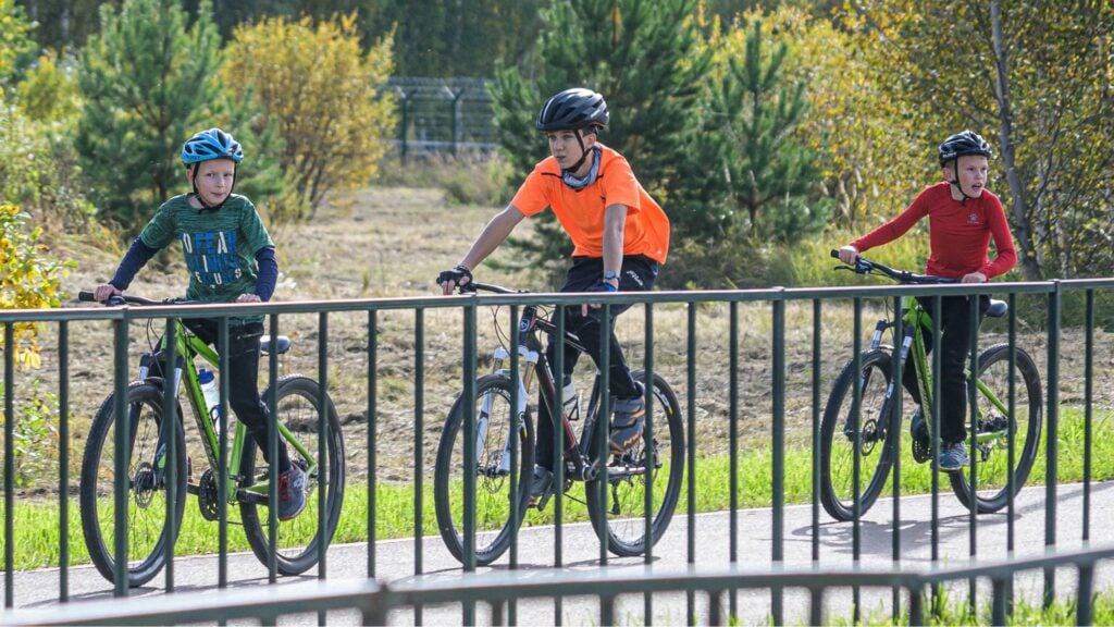 3 teenage boys riding their bikes along a bike path