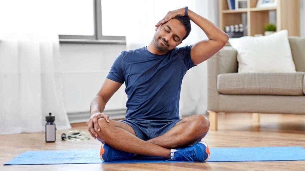 Man stretching on yoga mat at home