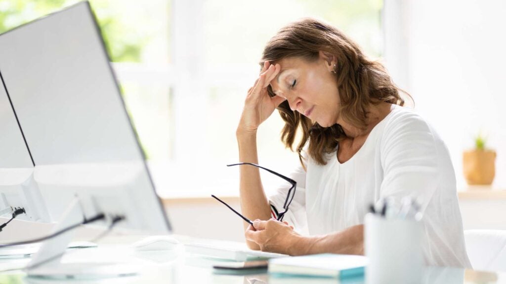 Stressed woman holding her head while sitting at computer desk