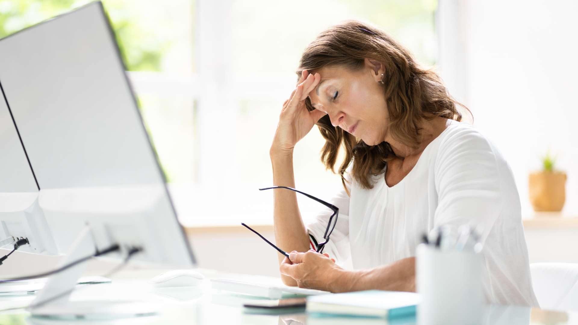 Stressed woman holding her head while sitting at computer desk