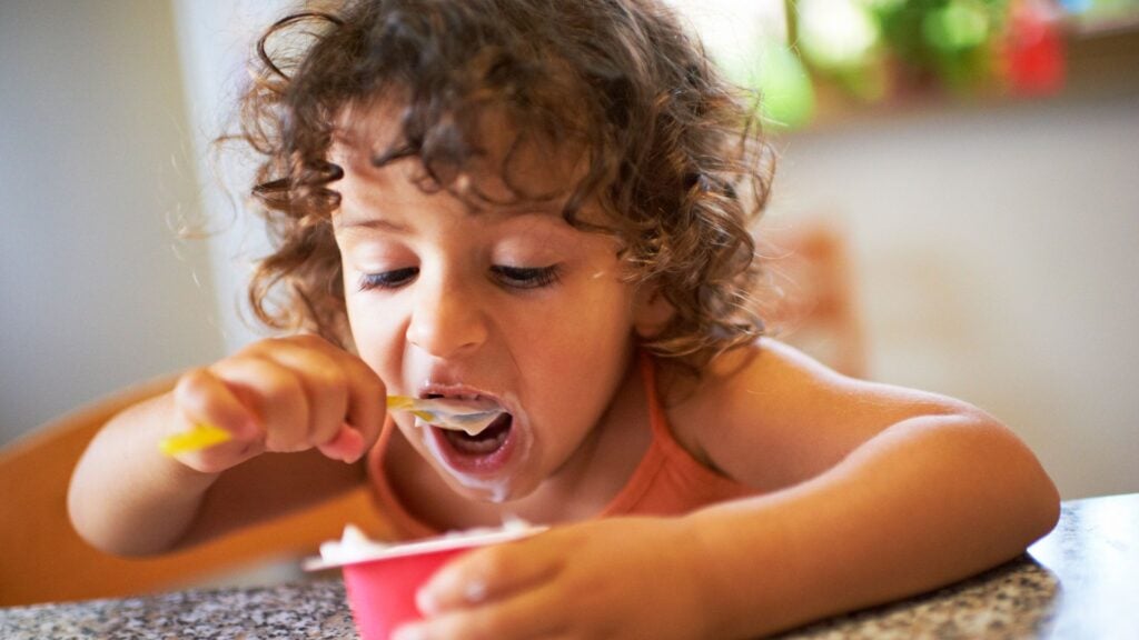Young girl eats yoghurt