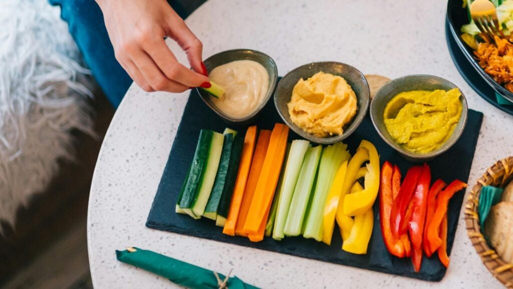 Person dips vegetable stick into dip