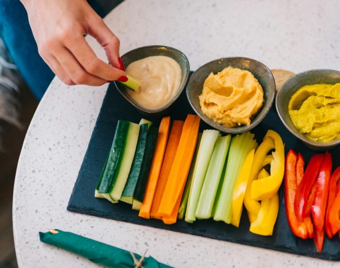 Person dips vegetable stick into dip