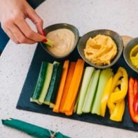 Person dips vegetable stick into dip