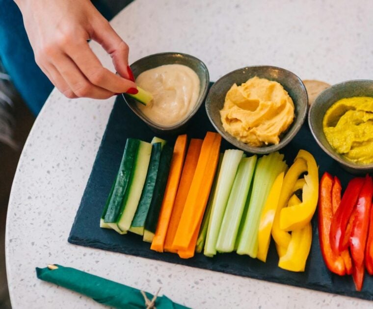 Person dips vegetable stick into dip