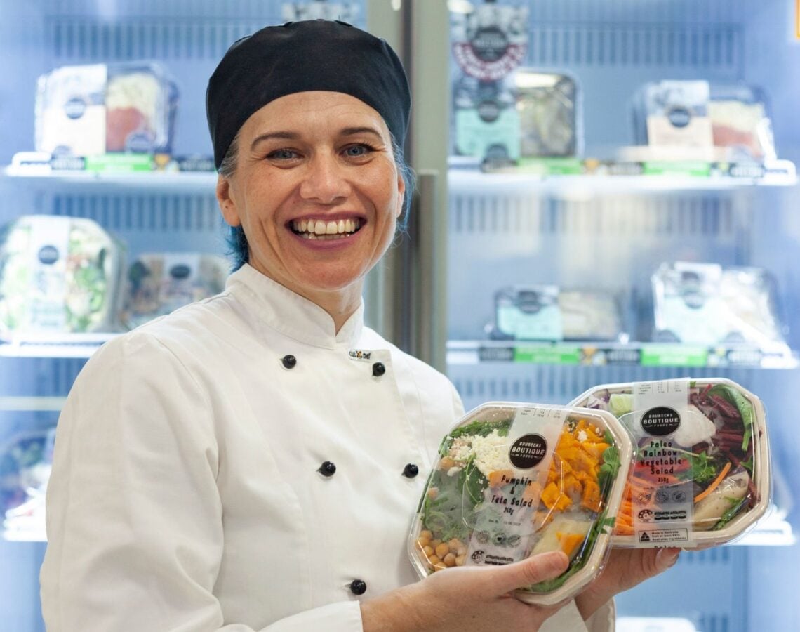 Chef with healthy meal options stands in front of cafeteria fridge