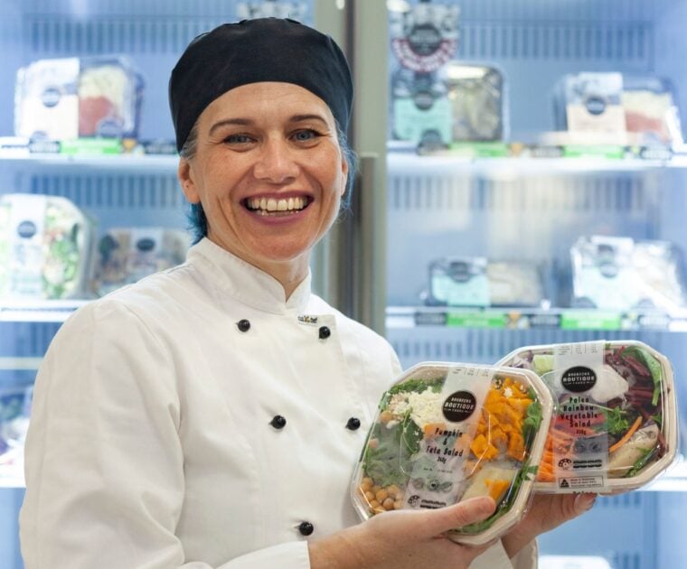 Chef with healthy meal options stands in front of cafeteria fridge