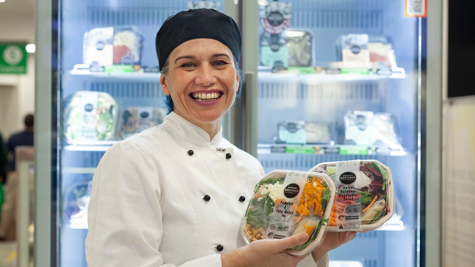 Chef with healthy meal options stands in front of cafeteria fridge