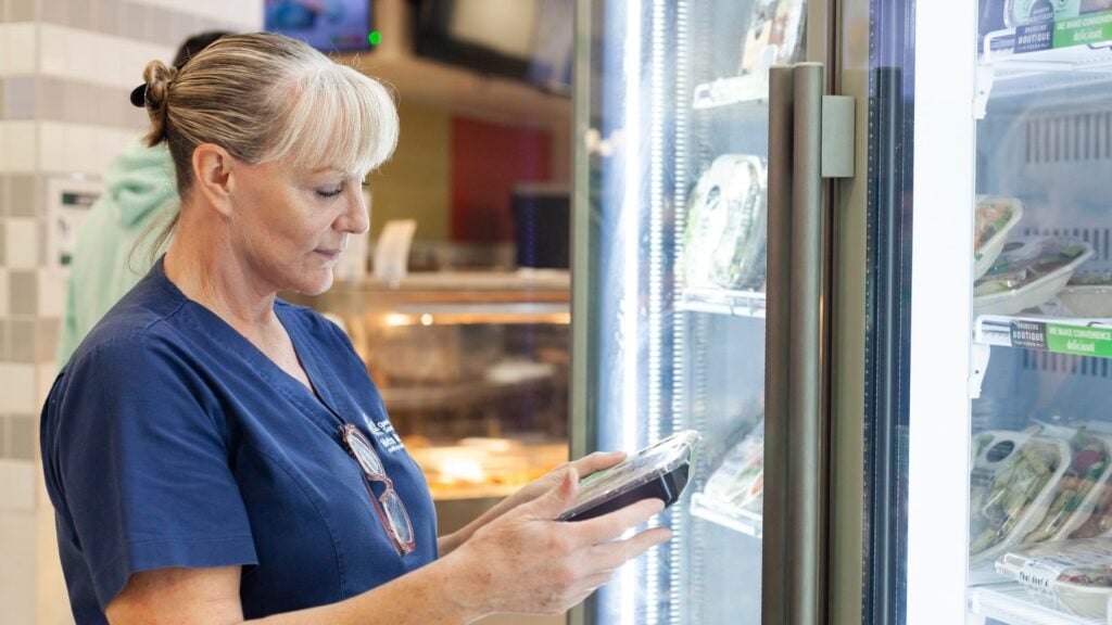 Healthcare worker looks at packaged salad in hospital cafeteria