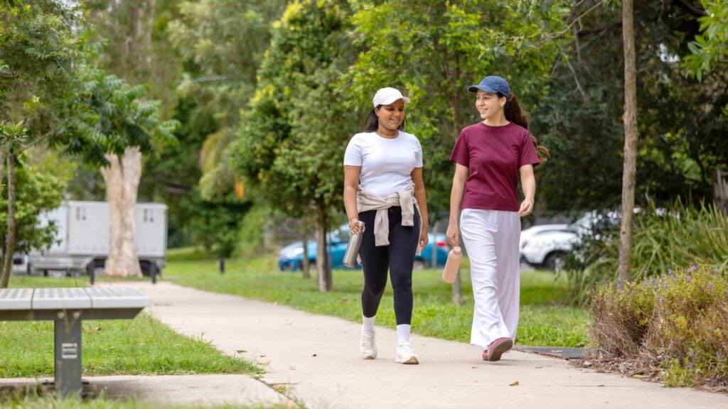 Two women walk along a footpath together