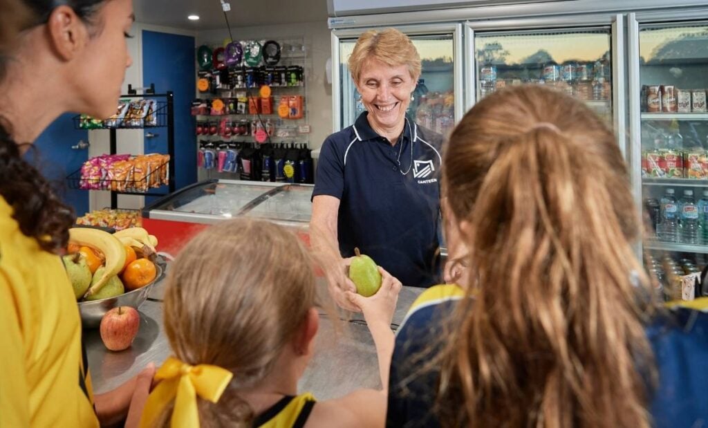 Kids being served healthy food and drinks options at a sports club canteen