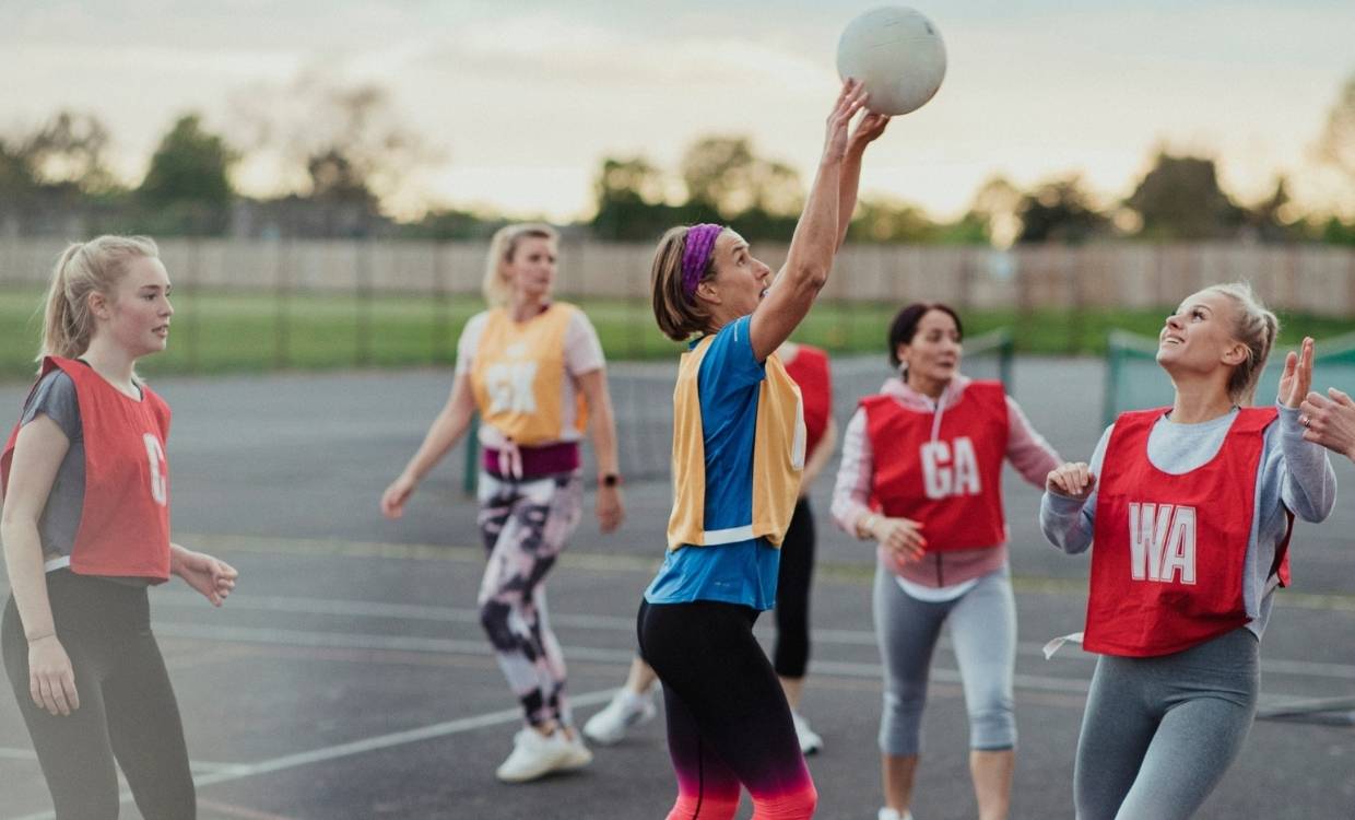 Women playing a social game of netball outdoors