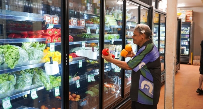 Woman restocking vegetables in fridge in remote store