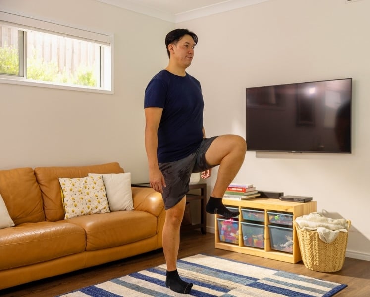 Man doing step up knee lifts in lounge room