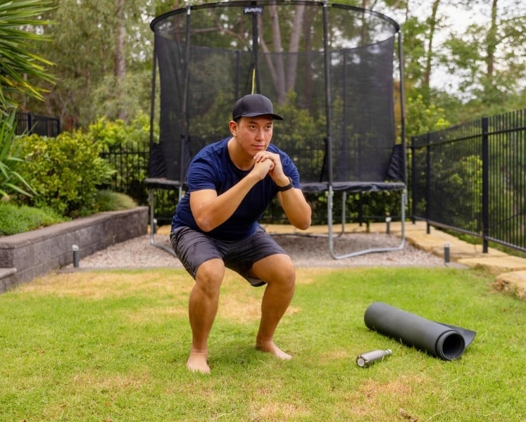Man doing squat exercise in back yard