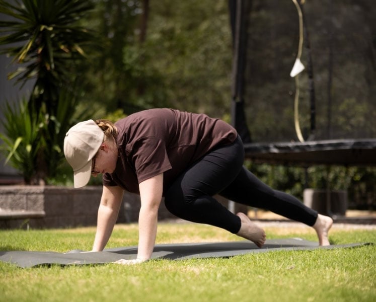 Woman performing mountain climbers on a workout mat in the backyard