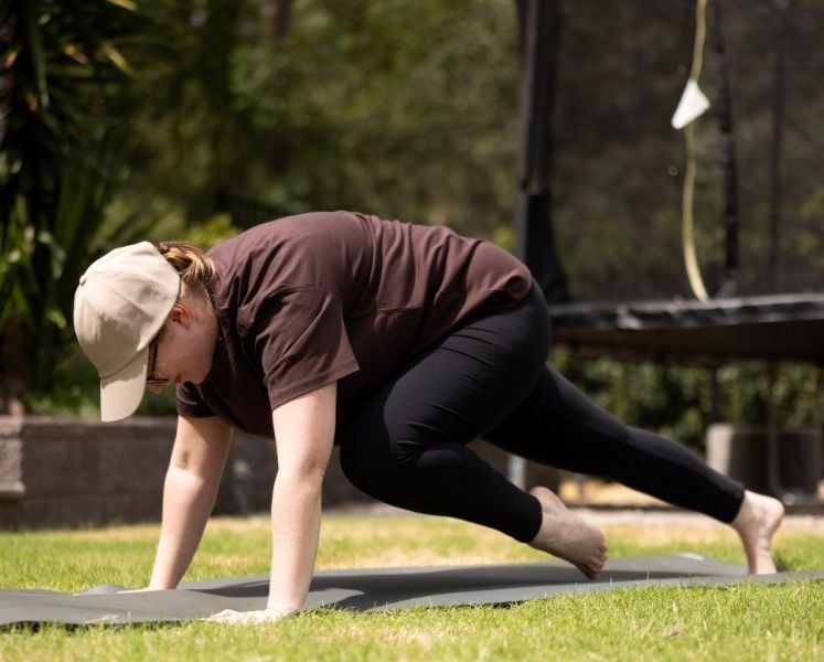 Woman performing mountain climbers on a workout mat in the backyard