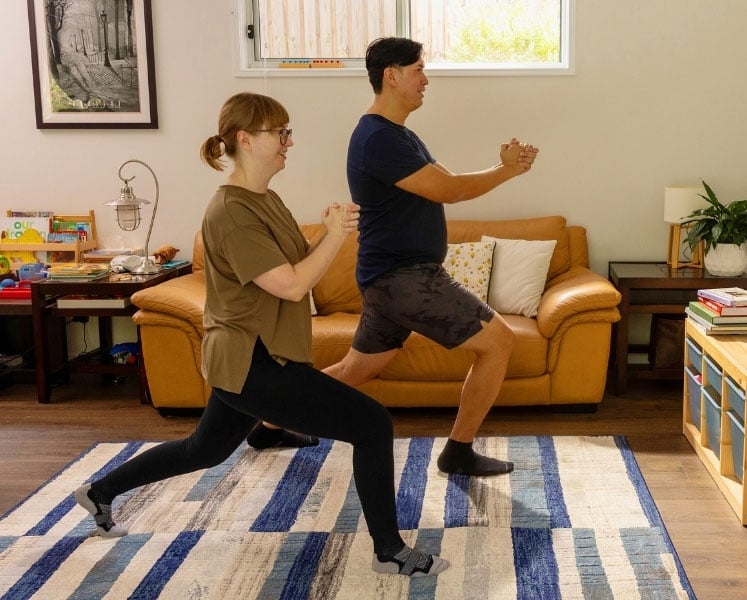 Quick lunch-break workout: couple doing lunges in lounge room