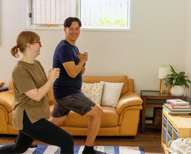 Quick lunch-break workout: couple doing lunges in lounge room