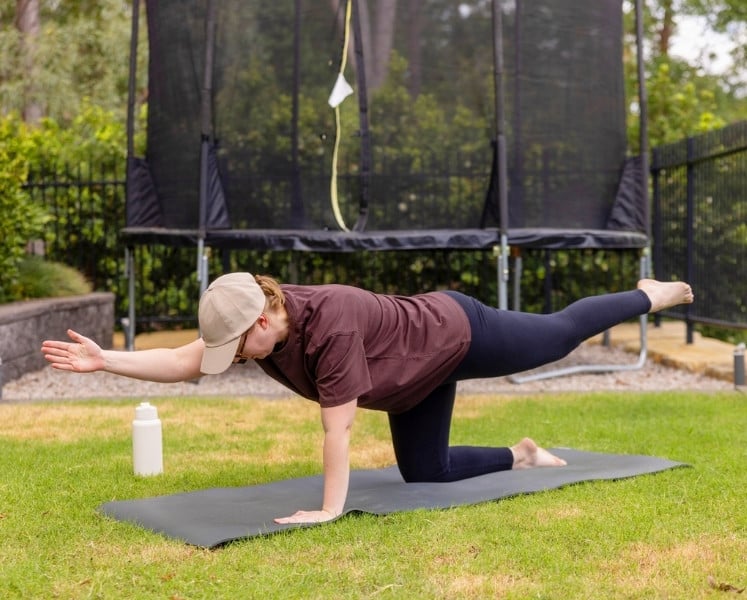 Woman outside in back yard doing stretching and strength exercises
