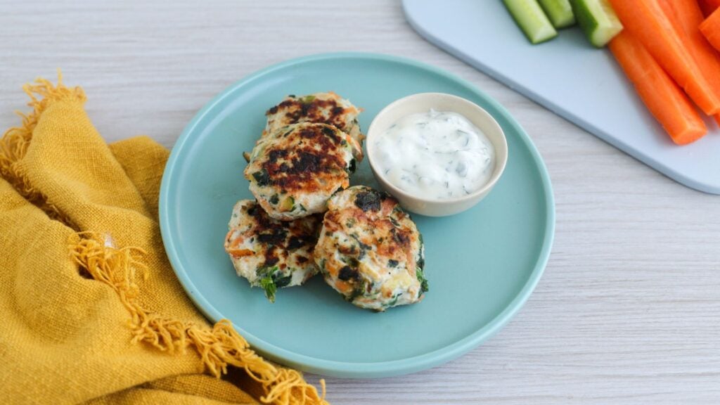 3 chicken and vegetables nuggets on a plate with yoghurt dipping sauce