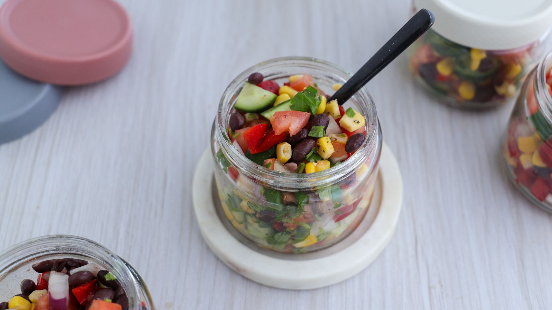 Beans, corn, tomato, cucumber and parsley in a glass mason jar