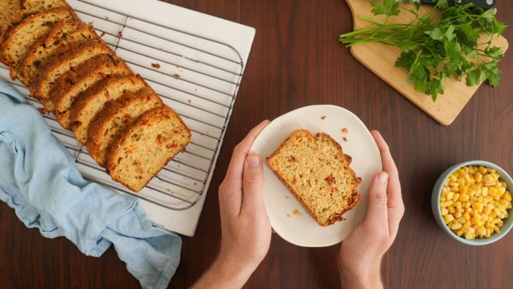 Sliced corn, tomato and cheese loaf with one slice on a plate