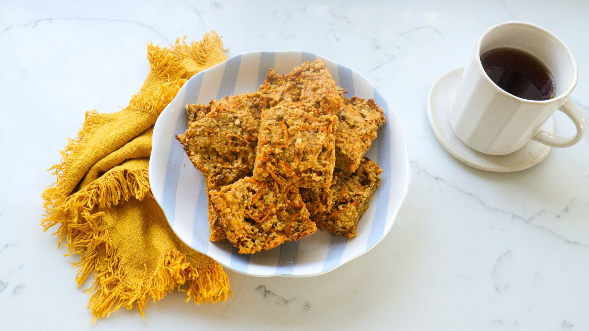 Carrot cake oat bar slices in a bowl beside a mug of black coffee