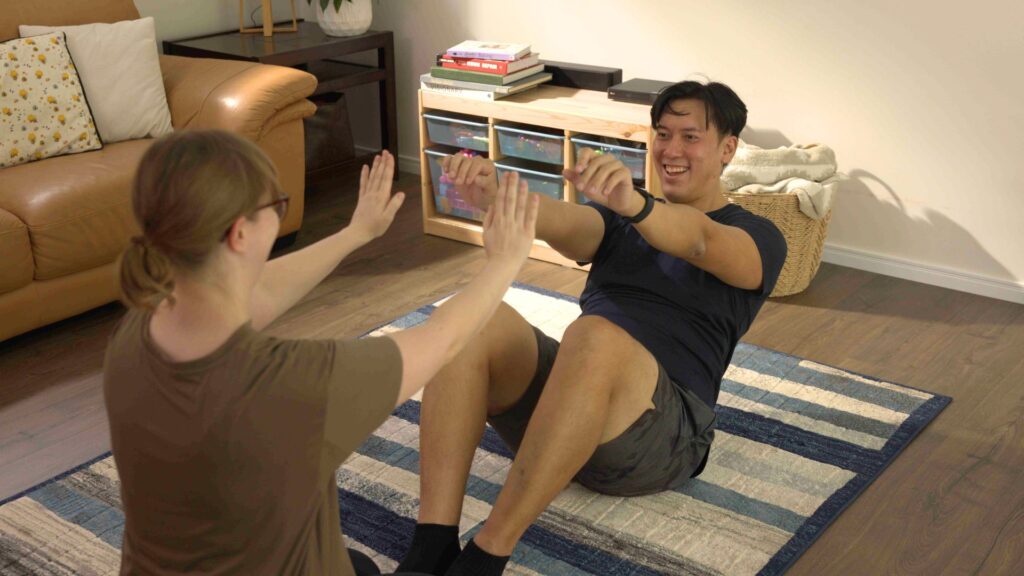 Women spots man while he does a sit up in the living room