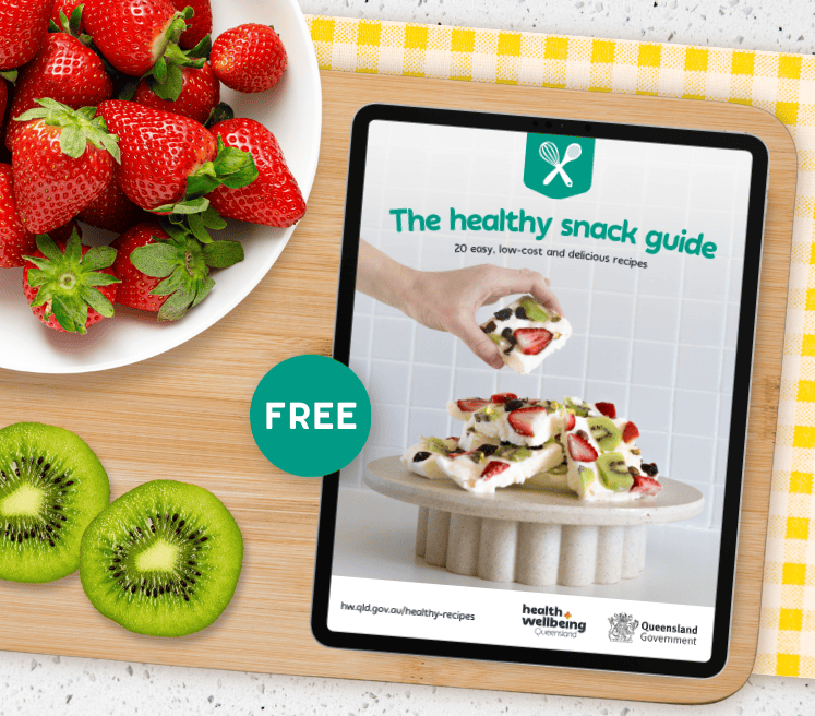 The healthy snack guide packed with 20 delicious recipes, shown on an iPad placed on a kitchen bench with chopping board and fresh fruit