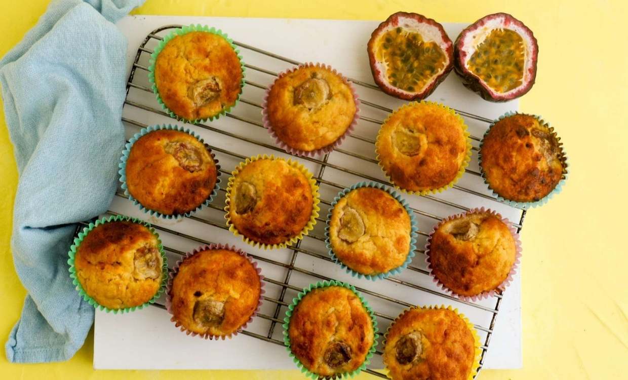 A dozen tropical fruit muffins sit on a wire cooling rack