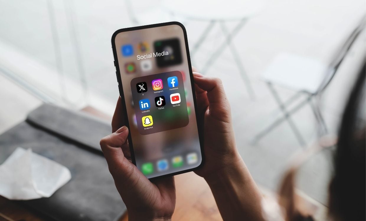 Person holding a phone with a collection of social media apps on screen