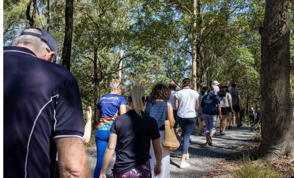 Group of people walking on outdoor path surrounded by large trees