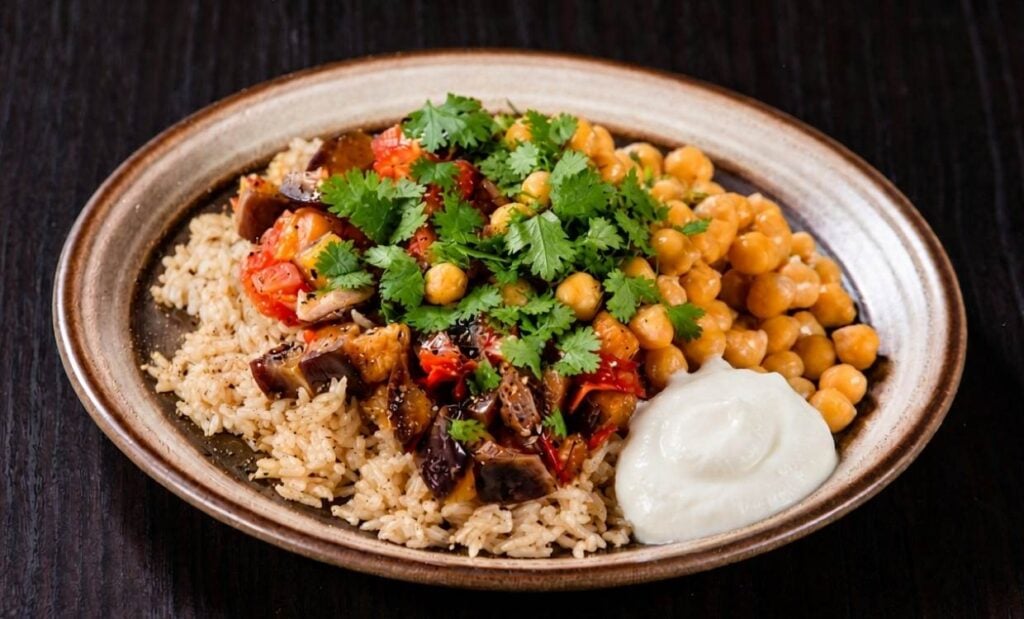 A plate filled with roasted chickpeas, brown rice, strawberry chutney, natural yoghurt and sprinkled with fresh corriander