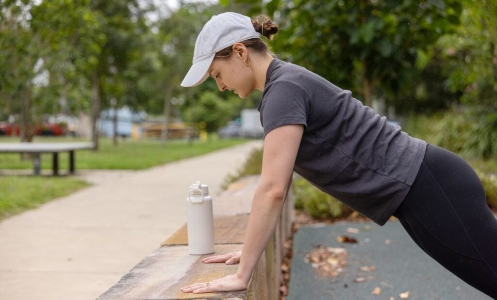 Women does a modified push up against a retaining wall