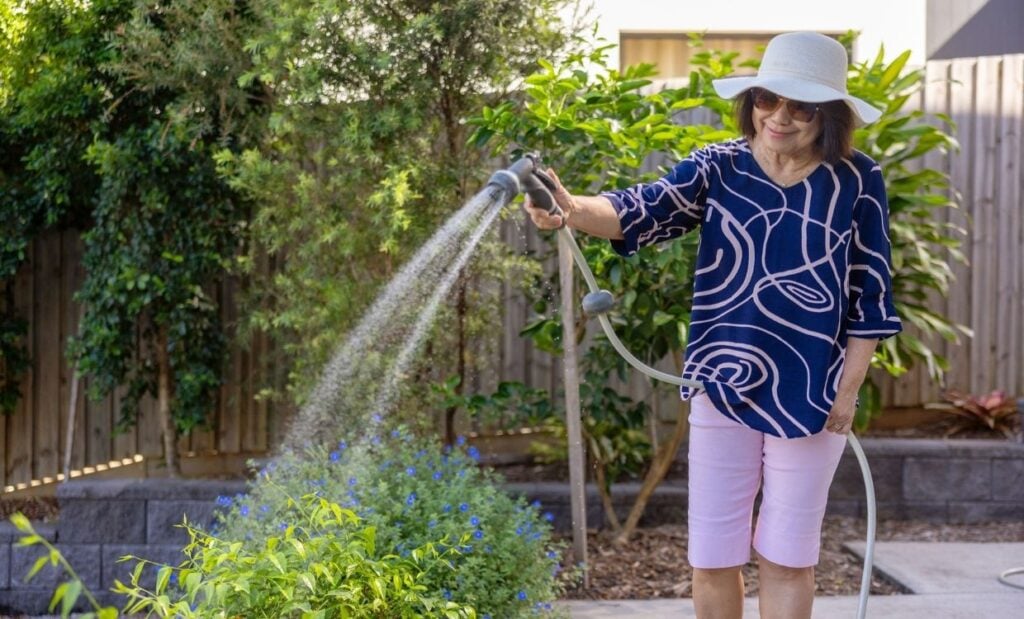 Older woman waters her plants outdoors