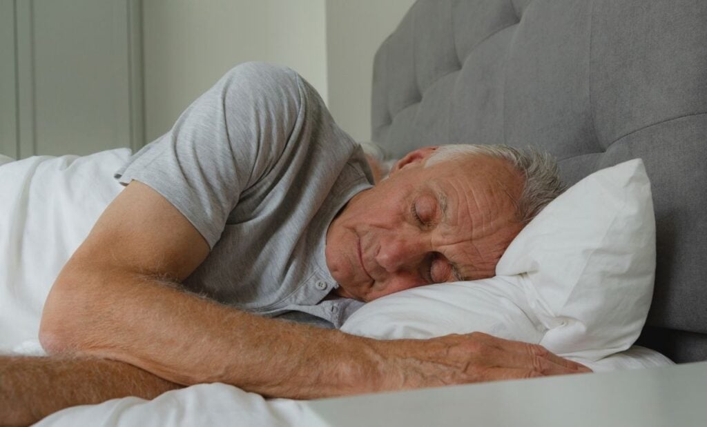 Older man sleeps in bed